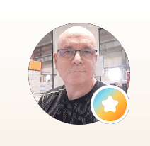 Portrait d'un homme chauve à lunettes dans un cadre circulaire avec un badge étoilé coloré.